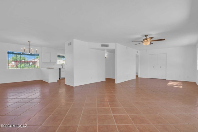 unfurnished living room with light tile patterned flooring, visible vents, ceiling fan with notable chandelier, and a sink