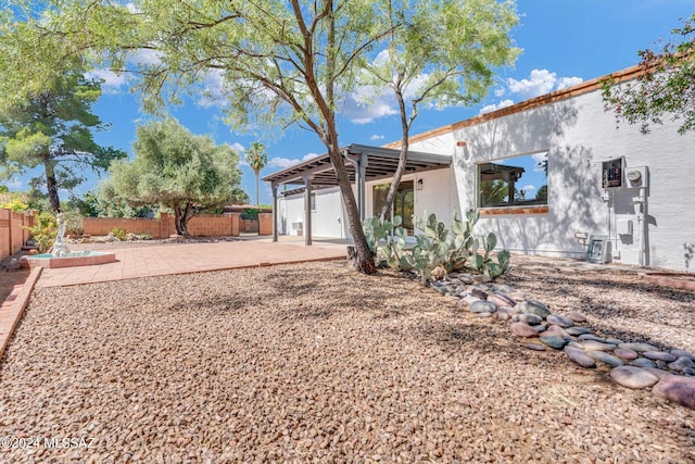 view of front of home featuring stucco siding, a fenced backyard, and a patio area