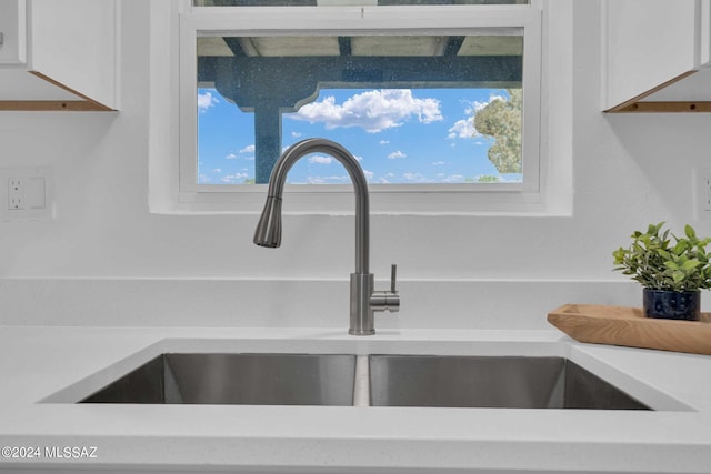 interior details featuring a sink, light countertops, and white cabinetry