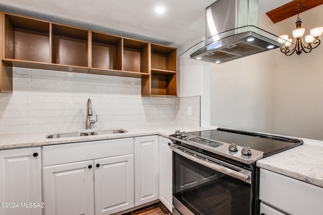 kitchen featuring stainless steel electric range oven, white cabinetry, a chandelier, sink, and island exhaust hood