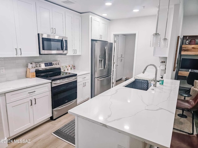 kitchen with light wood-style flooring, a sink, stainless steel appliances, white cabinetry, and backsplash