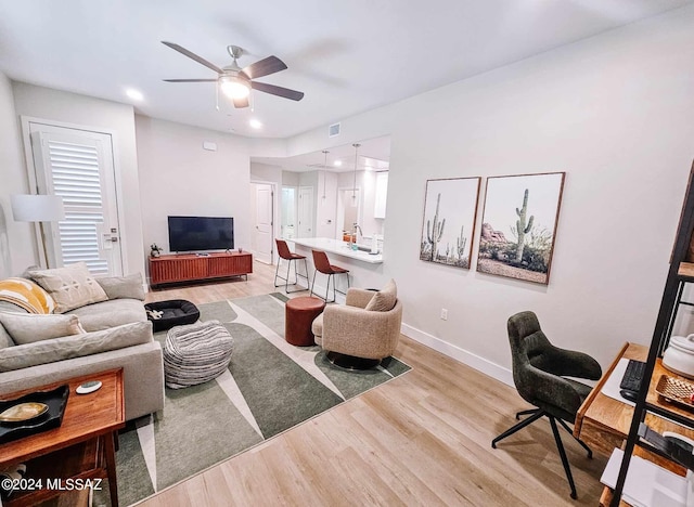 living area with light wood-style floors, visible vents, ceiling fan, and baseboards