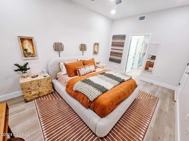 bedroom with visible vents, baseboards, a ceiling fan, connected bathroom, and light wood-style flooring