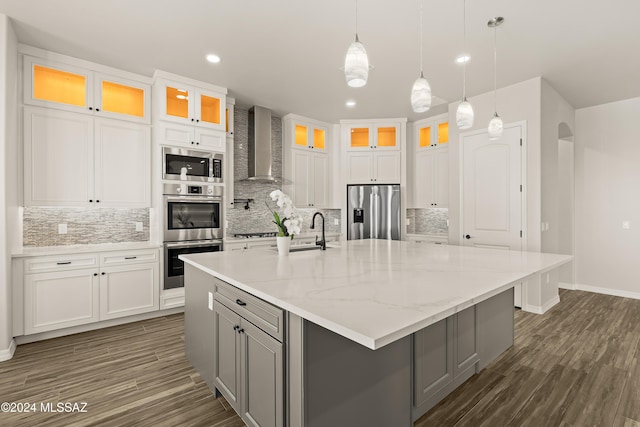 kitchen featuring white cabinets, appliances with stainless steel finishes, wall chimney exhaust hood, and a large island