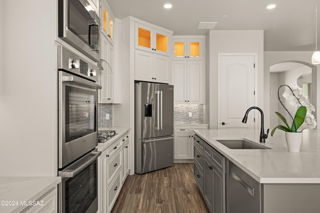 kitchen featuring white cabinets, appliances with stainless steel finishes, light stone countertops, and sink