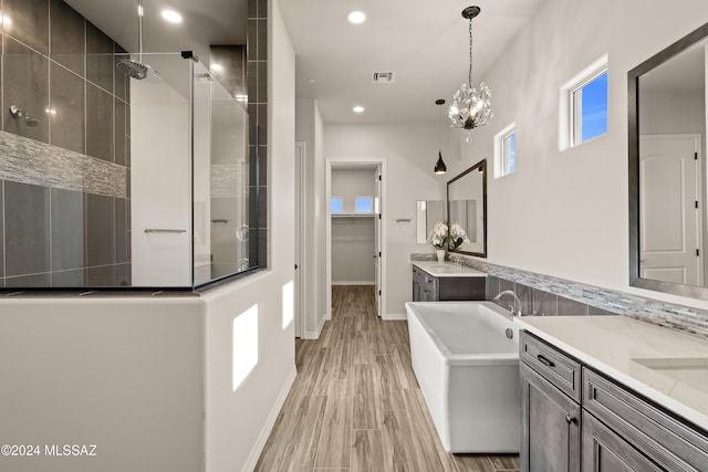 bathroom with a chandelier, shower with separate bathtub, vanity, and wood-type flooring