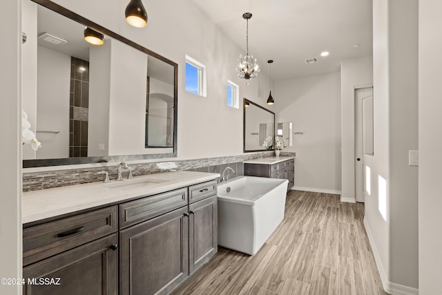 bathroom with vanity, wood-type flooring, a tub to relax in, and a chandelier