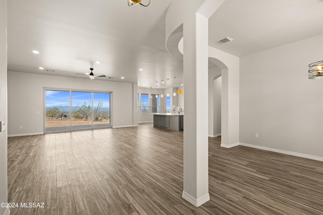 unfurnished living room featuring ceiling fan and dark wood-type flooring