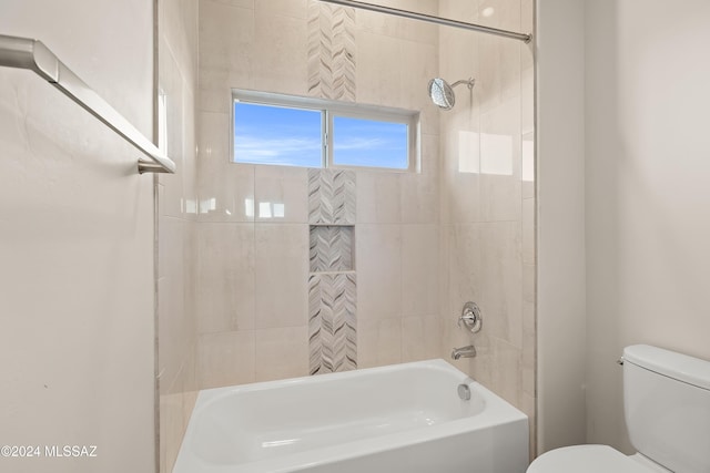 bathroom with tiled shower / bath combo and toilet