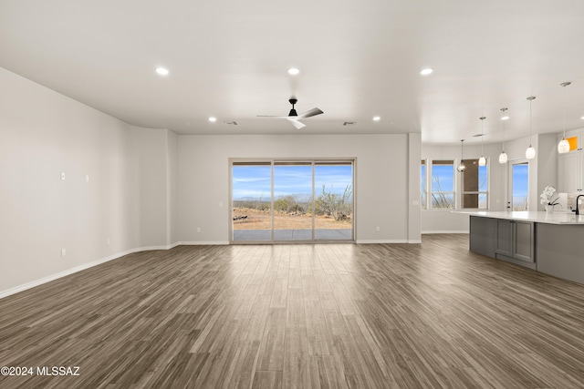 unfurnished living room featuring ceiling fan and dark hardwood / wood-style floors