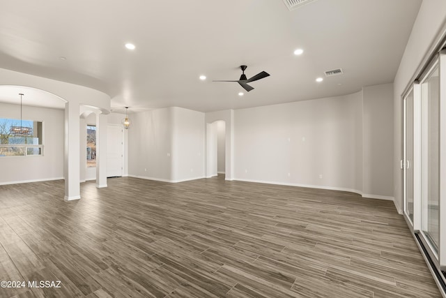 unfurnished living room with ceiling fan with notable chandelier and dark hardwood / wood-style floors