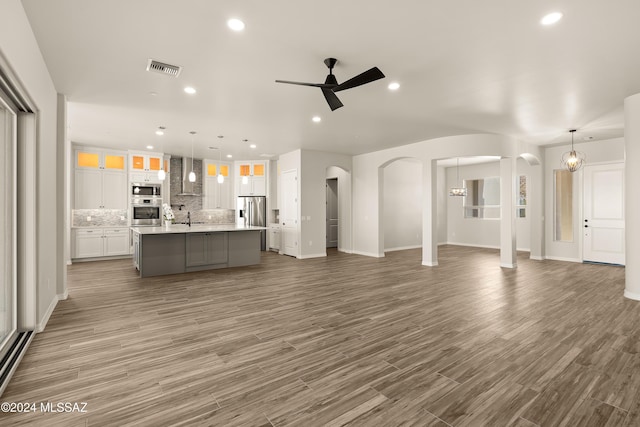 unfurnished living room featuring dark hardwood / wood-style floors, sink, and ceiling fan with notable chandelier