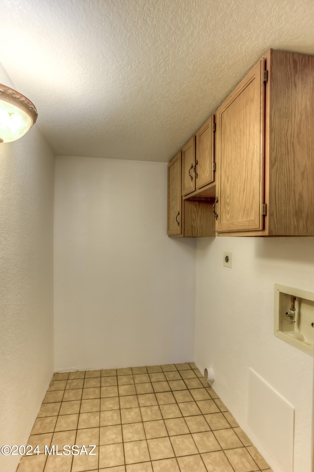 laundry area with cabinets, electric dryer hookup, a textured ceiling, washer hookup, and light tile patterned flooring