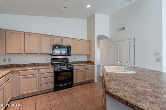 kitchen with black appliances, light tile patterned floors, sink, light brown cabinets, and high vaulted ceiling