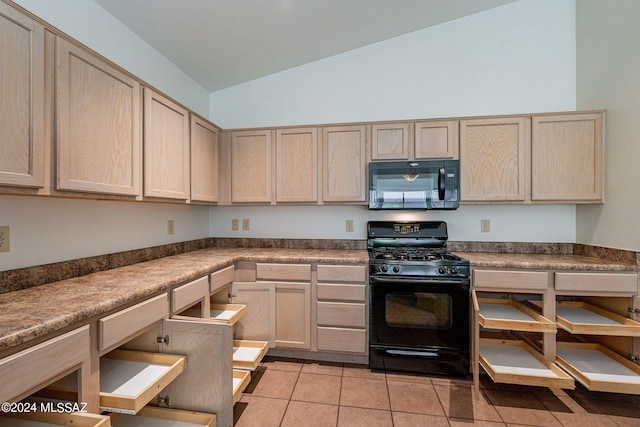 kitchen with black appliances, light brown cabinetry, light tile patterned floors, and vaulted ceiling