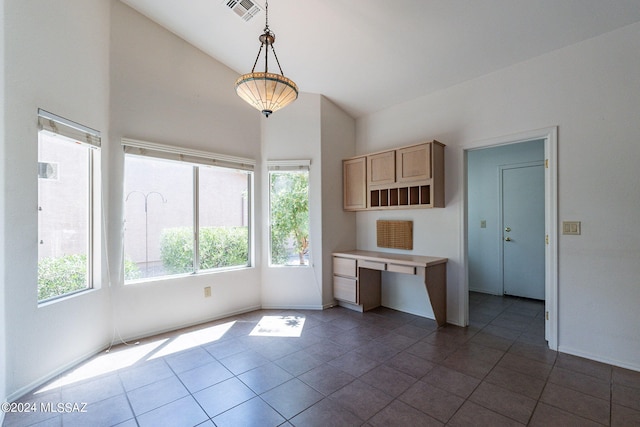 kitchen featuring lofted ceiling, pendant lighting, dark tile patterned flooring, and light brown cabinetry