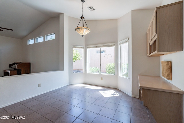 unfurnished dining area featuring baseboards, visible vents, ceiling fan, tile patterned flooring, and vaulted ceiling