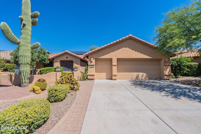 view of front facade featuring solar panels, an attached garage, stucco siding, concrete driveway, and a tiled roof