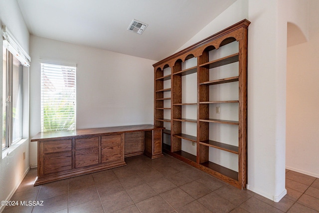 unfurnished office with visible vents, baseboards, dark tile patterned floors, and vaulted ceiling