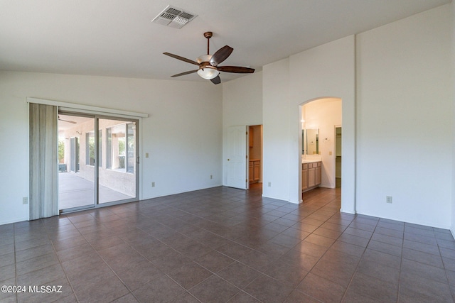 spare room featuring visible vents, ceiling fan, dark tile patterned floors, arched walkways, and high vaulted ceiling