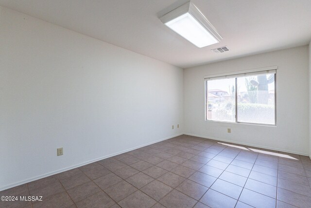 empty room with tile patterned floors, visible vents, and baseboards