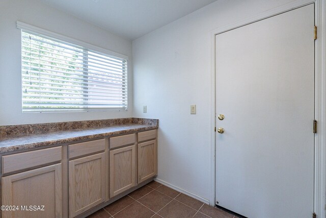 interior space with light brown cabinets and dark tile patterned floors