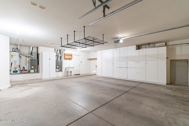 garage featuring gas water heater, a garage door opener, and heating unit