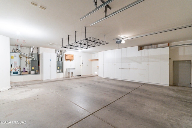 garage with heating unit, gas water heater, and a garage door opener