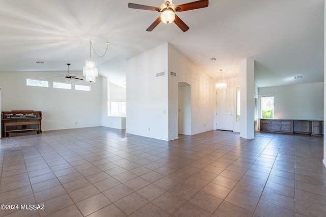 unfurnished living room featuring ceiling fan, vaulted ceiling, light tile patterned flooring, and a healthy amount of sunlight