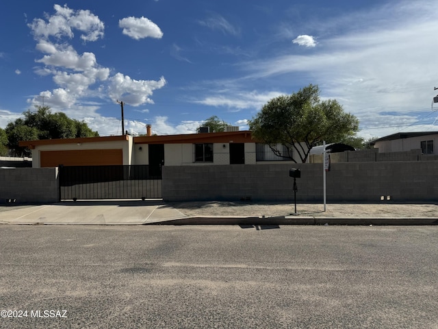 ranch-style house featuring a fenced front yard, concrete block siding, and a gate