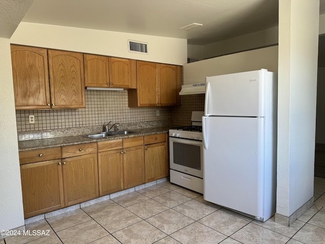 kitchen featuring white appliances, visible vents, a sink, under cabinet range hood, and backsplash