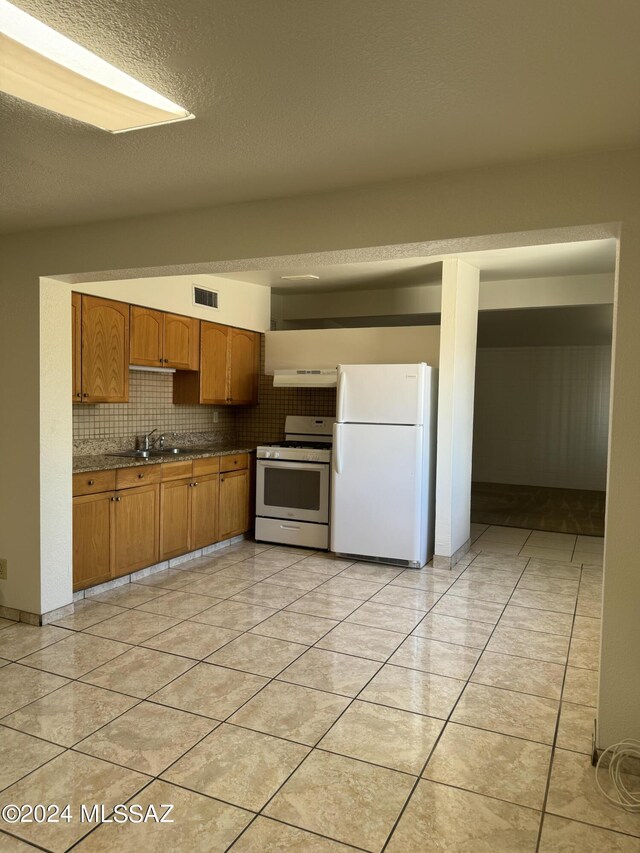 kitchen with sink, light tile patterned floors, white appliances, and decorative backsplash