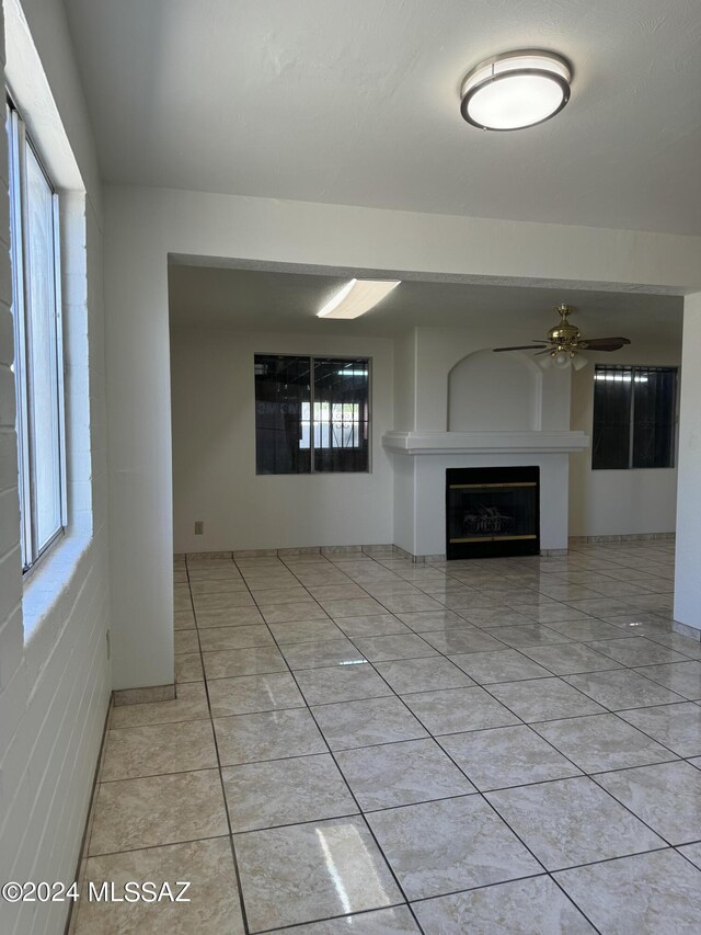 unfurnished living room with a wealth of natural light and ceiling fan