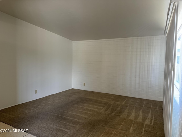 unfurnished room featuring dark carpet