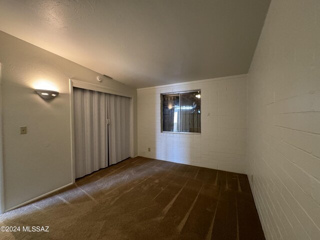 carpeted empty room featuring a textured ceiling and vaulted ceiling