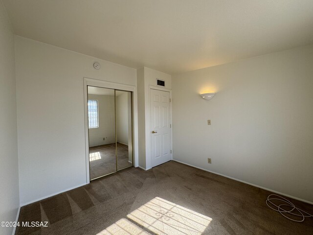 unfurnished bedroom featuring visible vents, carpet floors, and a closet