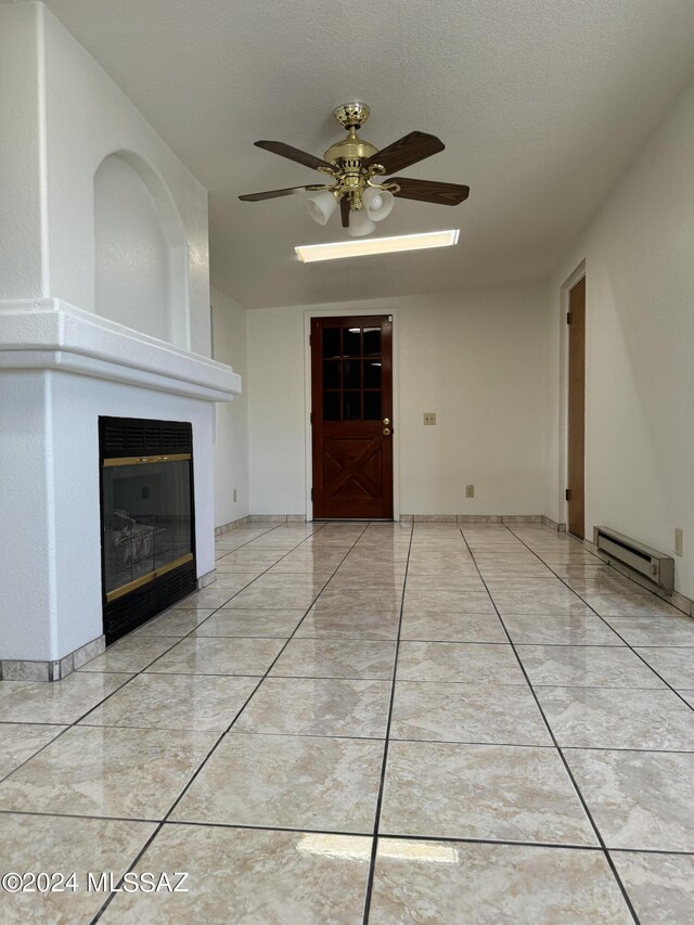 unfurnished living room featuring a baseboard heating unit, ceiling fan, and a textured ceiling