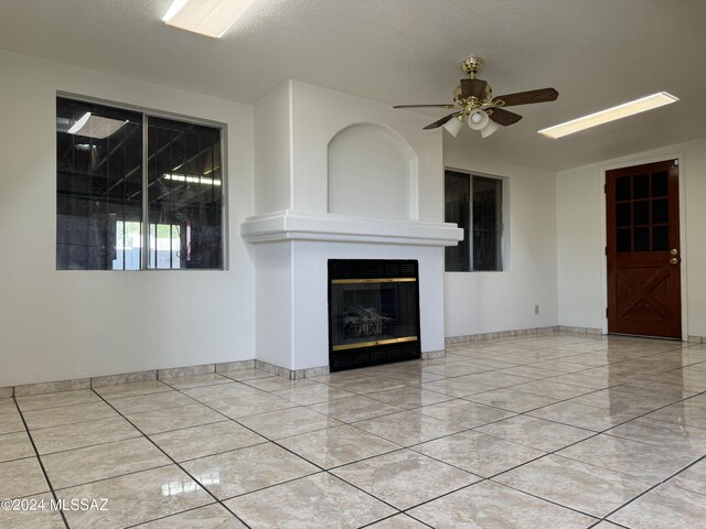 unfurnished living room featuring a textured ceiling, ceiling fan, and a fireplace