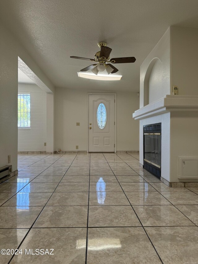 tiled foyer entrance with a textured ceiling and ceiling fan