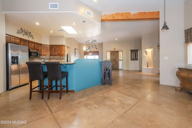 kitchen featuring a skylight, a kitchen bar, kitchen peninsula, appliances with stainless steel finishes, and beam ceiling