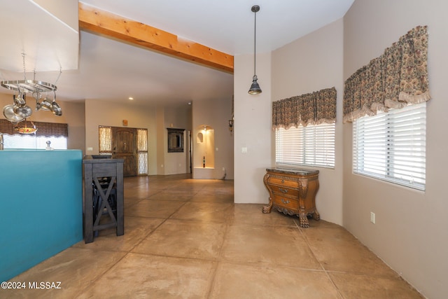 hallway with beamed ceiling, a chandelier, and concrete floors