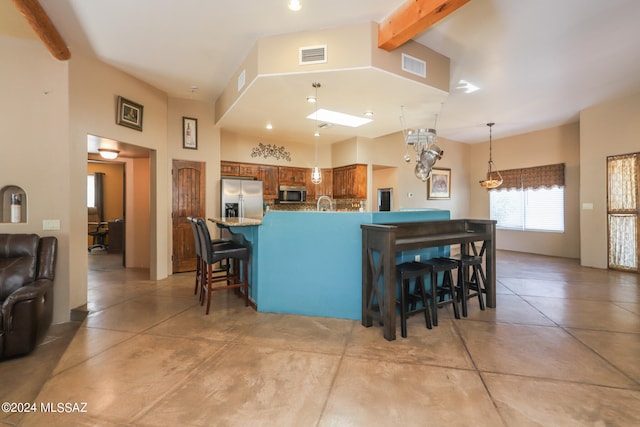 kitchen featuring kitchen peninsula, a breakfast bar area, appliances with stainless steel finishes, and beam ceiling