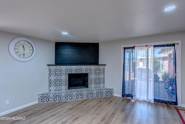 unfurnished living room with baseboards, wood finished floors, and a tile fireplace