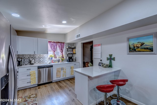 kitchen featuring a sink, appliances with stainless steel finishes, white cabinets, and light wood finished floors