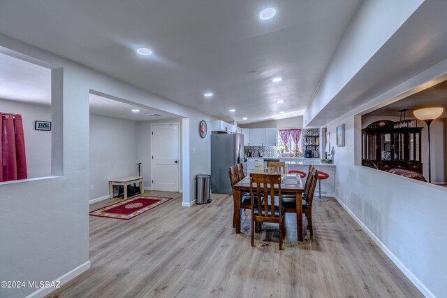 dining area with vaulted ceiling and light wood-type flooring