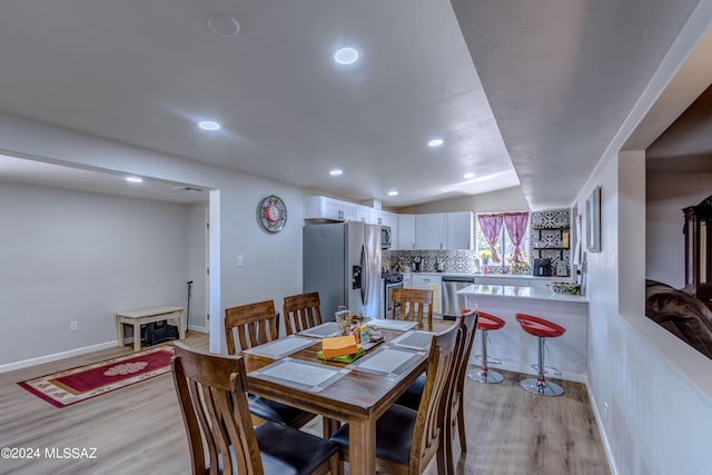 dining space featuring recessed lighting, baseboards, lofted ceiling, and light wood-style floors