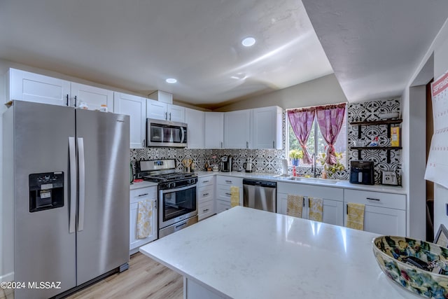 kitchen featuring backsplash, light countertops, appliances with stainless steel finishes, white cabinets, and a sink