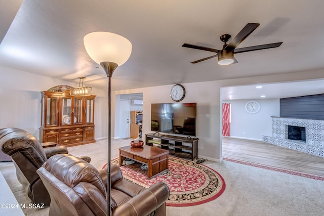 carpeted living room featuring ceiling fan and a fireplace