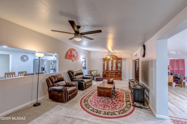 living room with carpet flooring, baseboards, and a ceiling fan