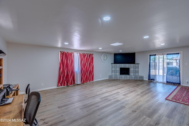 living room with a tiled fireplace and light hardwood / wood-style floors